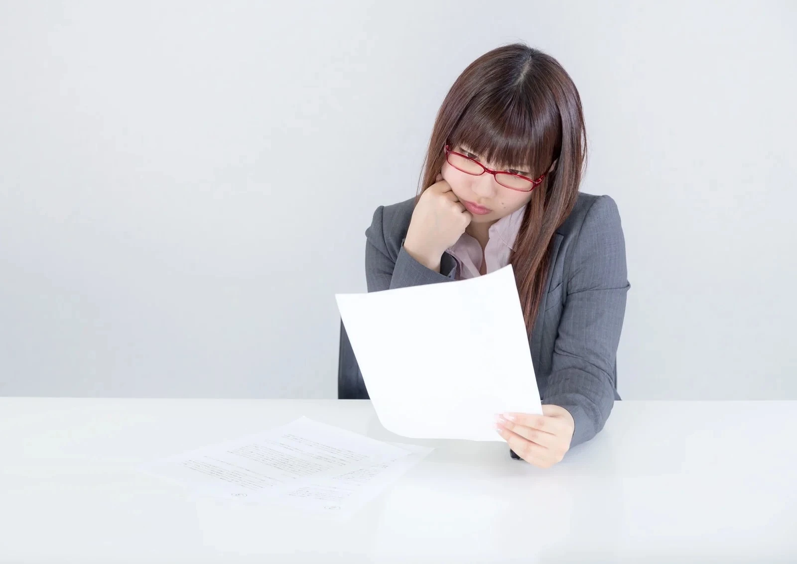 書類を見て物思いに耽る女性