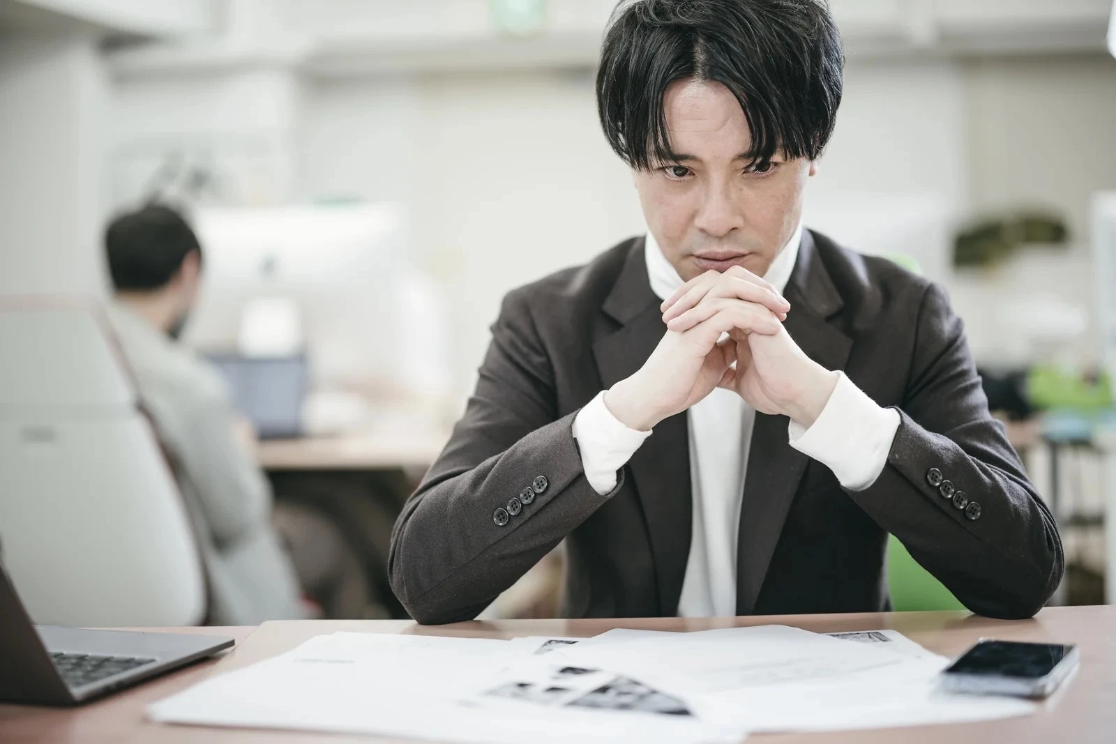 深刻な表情で机を見つめる男性