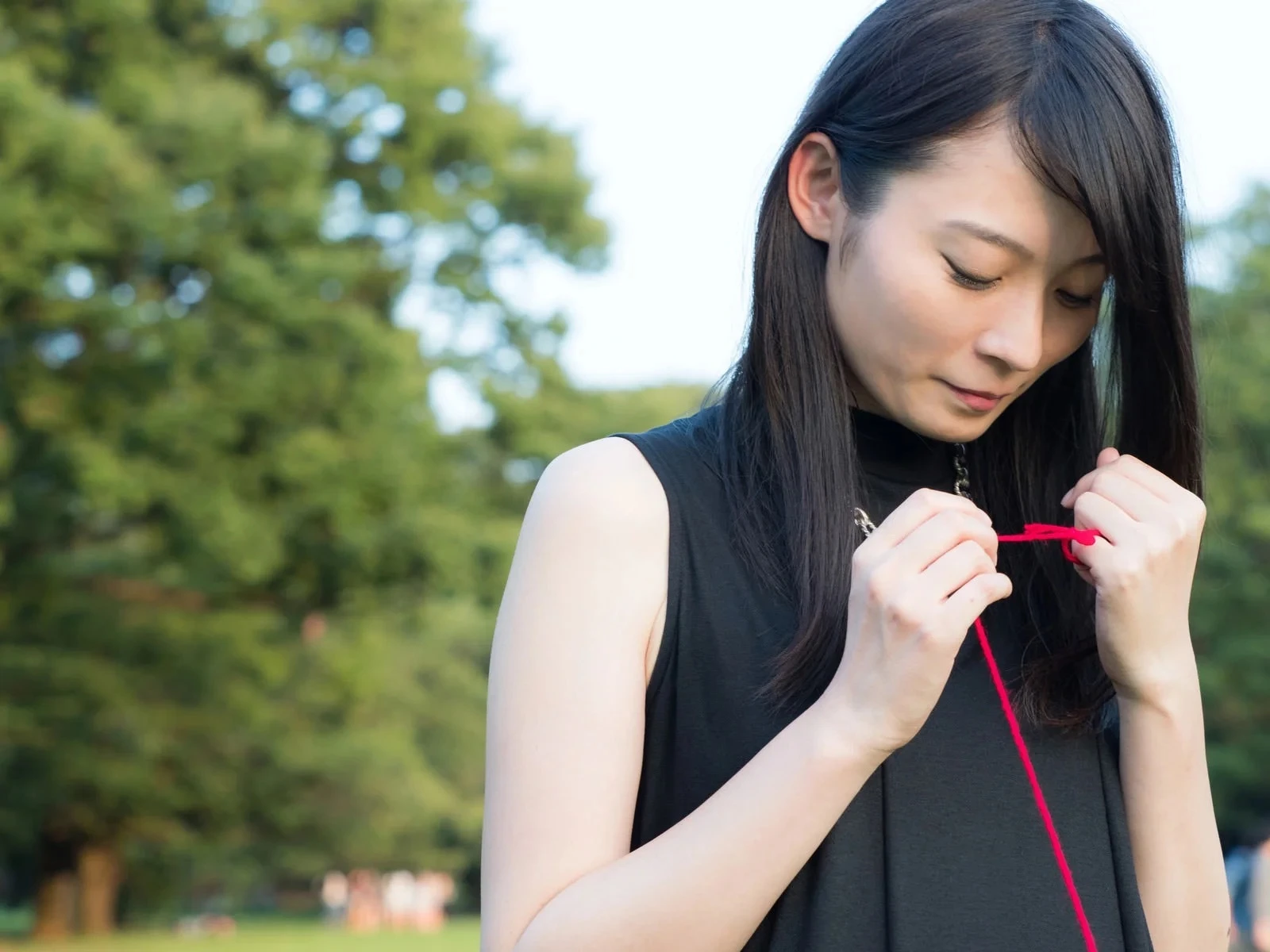 切れた赤い糸を結び直す若い女性