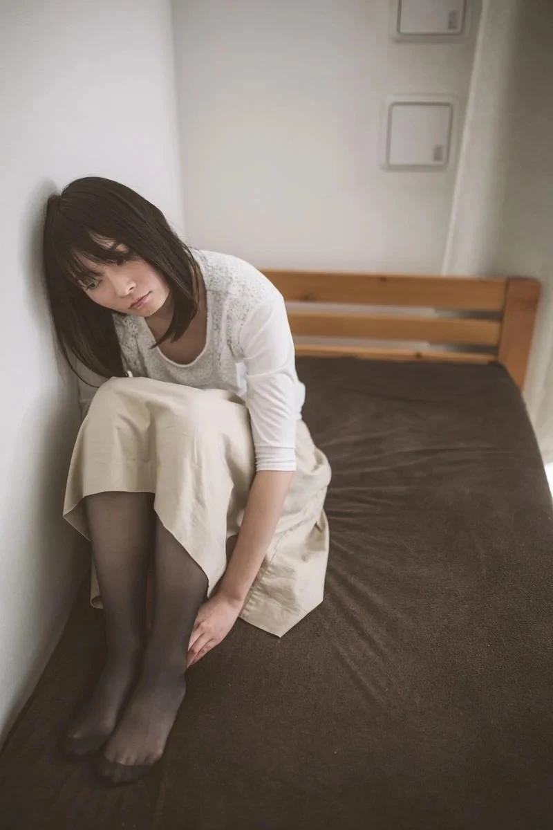 壁際に膝を抱えて座り込む女性