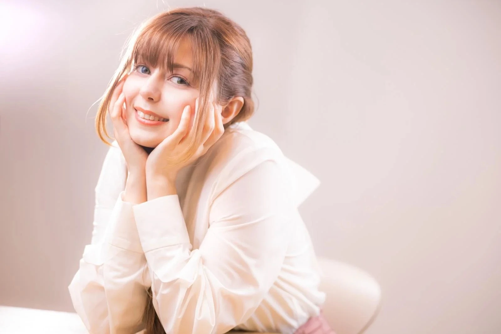 頬杖をつきながら明るく笑顔の若い女性