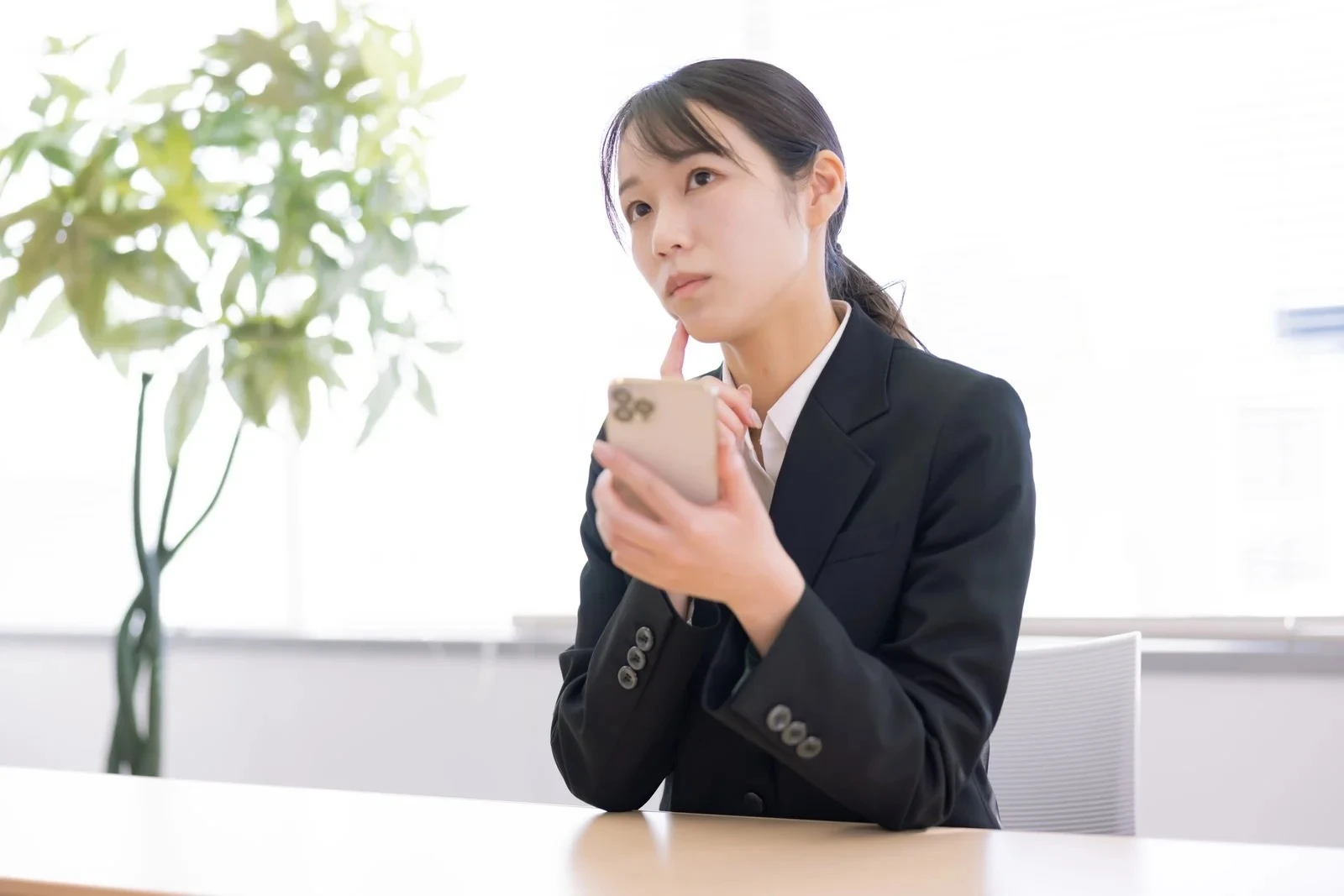 スマホを片手に首を傾げる女性