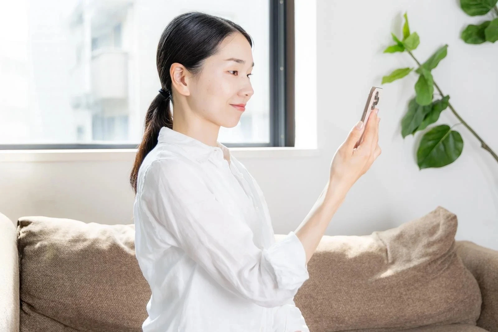窓際でスマホを見る若い女性