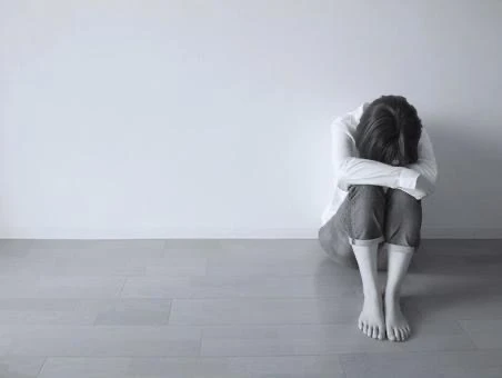 リビングの隅で膝を抱えている若い女性