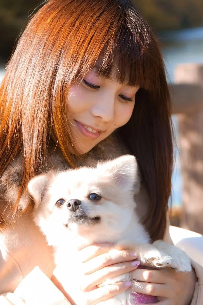散歩中の仔犬を抱く若い女性